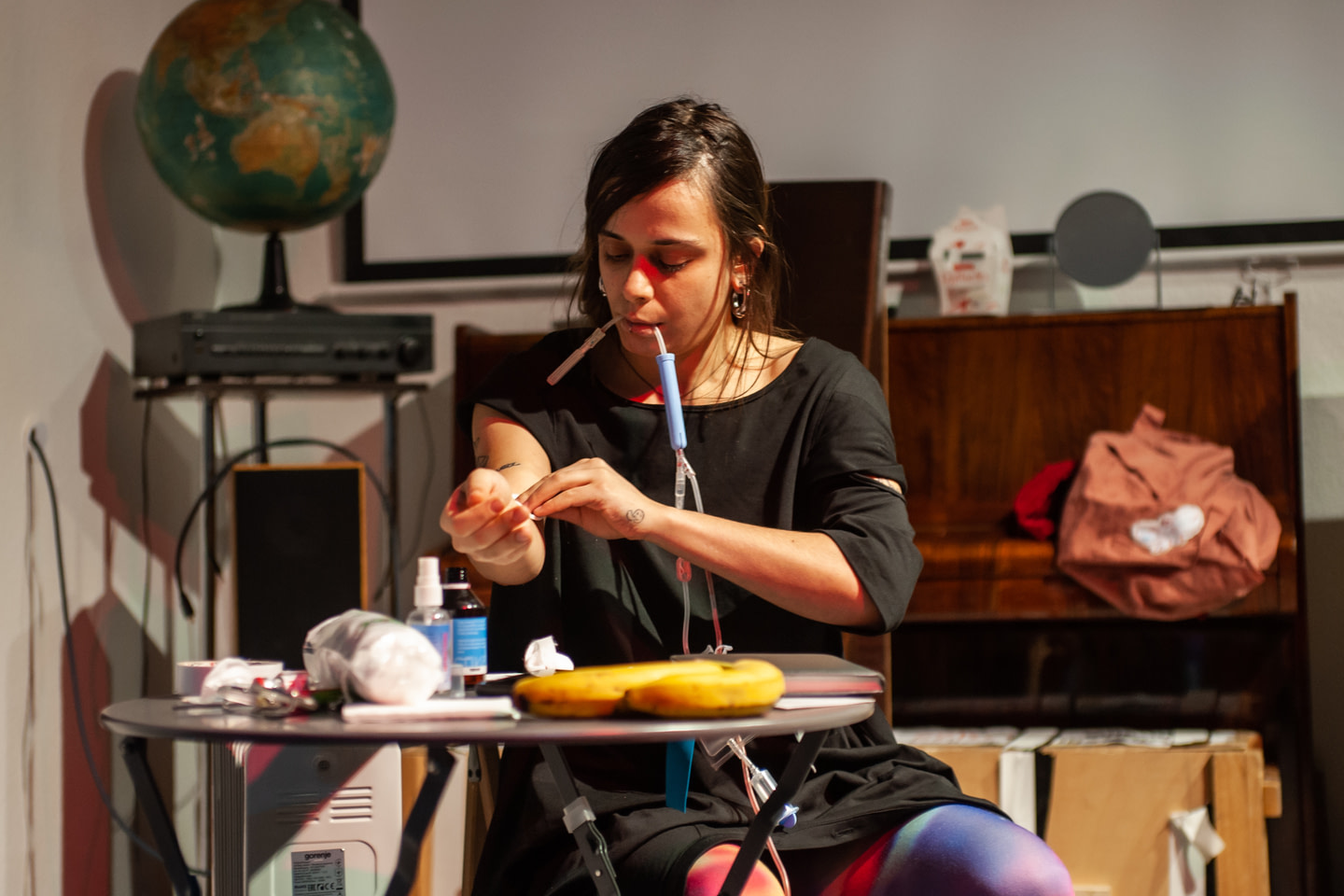 Kateryna Libkind at the performance “Zatsepka 1. Hold my bag” sits at a table and prepares her hand for a blood transfusion
